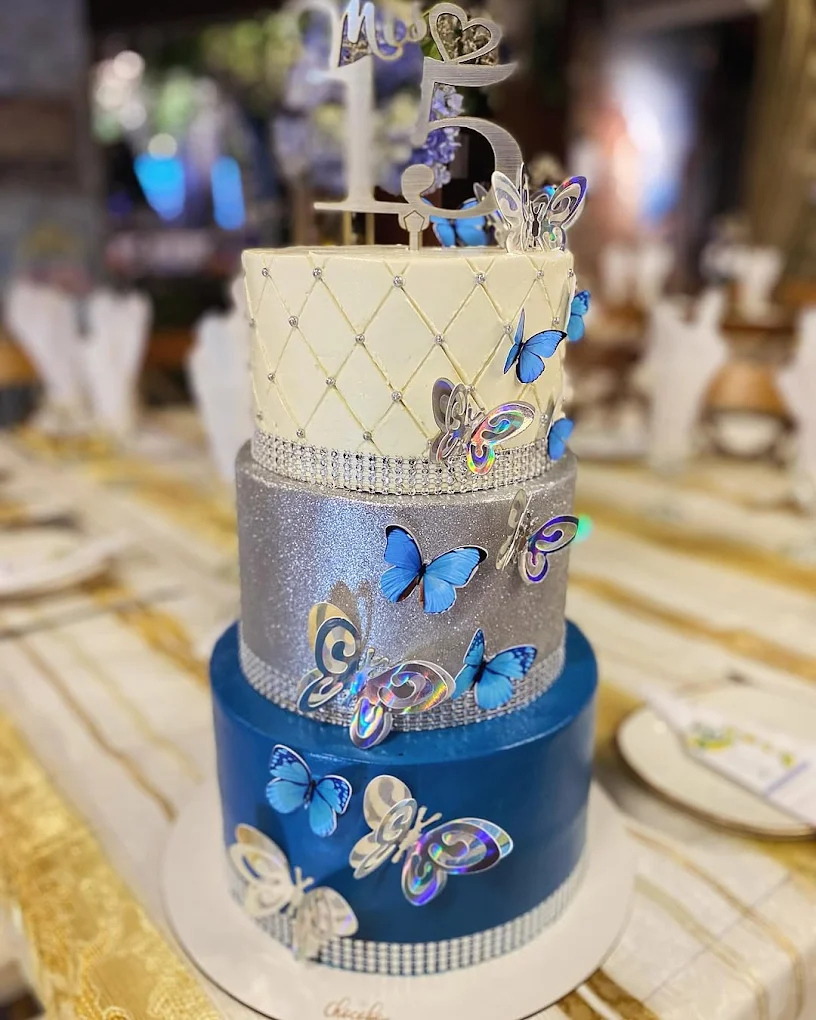Torta de quinceañera azul índigo con mariposas y detalles dorados