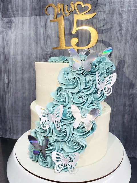 Torta de 15 años con rosetones turquesa en cascada y mariposas plateadas